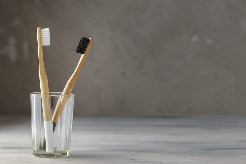 Two eco friendly bamboo tooth brushes in a glass. Zero Waste concept. Copy space for text